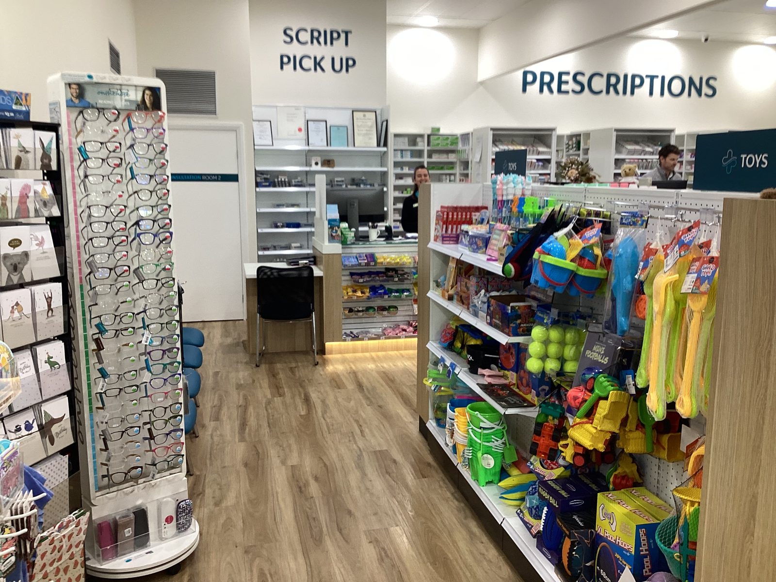 Pharmacy front-of-shop interior with toys, giftware and impulse retail displays near prescriptions counter